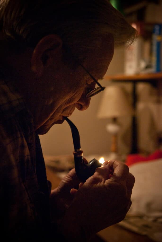 Grandpa Smoke lighting a pipe in a dark, cozy room.